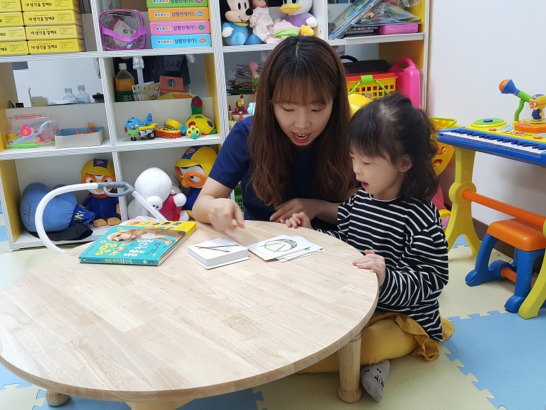 언어치료사가 아동과 함께 그림카드로 단어를 가르쳐주고 있는 모습