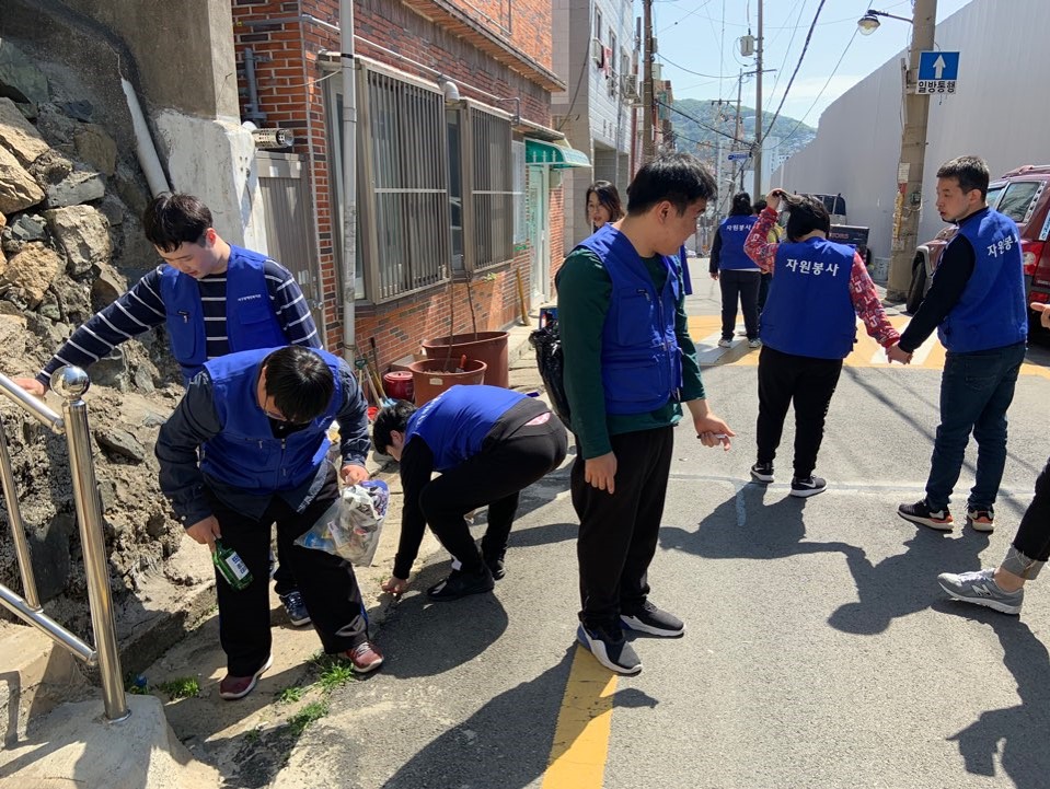 주간보호센터 이용자들이 파란 조끼를 입고 복지관 인근 거리의 쓰레기를 줍고 있는 모습