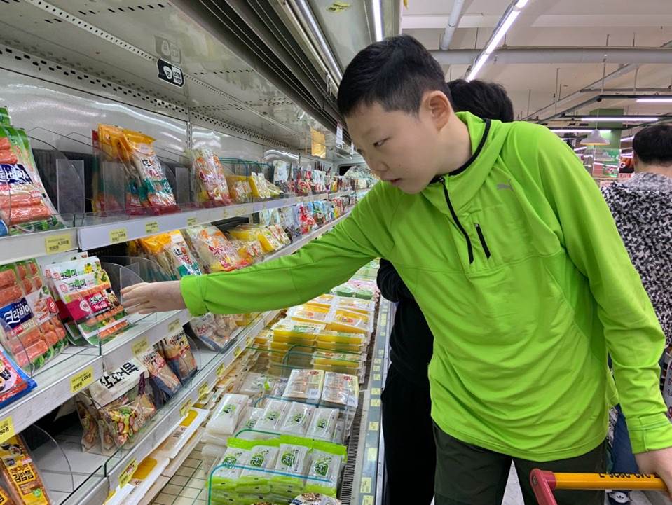 주간보호센터 이용자가 마트에서 맛살을 집으려 하고 있는 모습