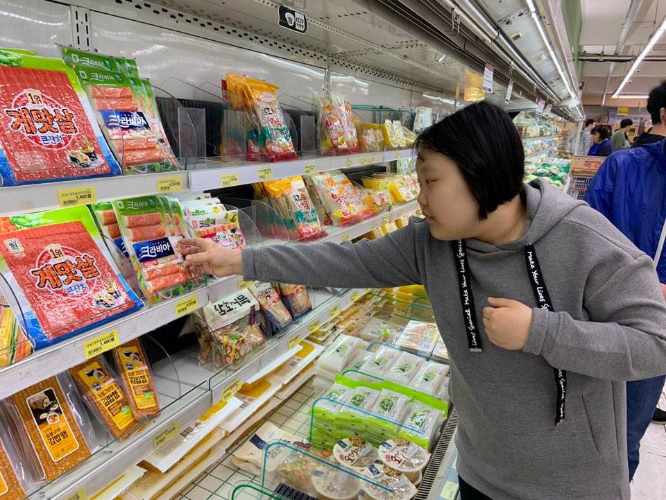주간보호센터 이용자가 마트에서 맛살을 집으려 하고 있는 모습
