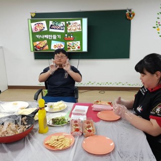 주간보호센터 이용자가 카나페 만들기 활동을 하다가 카메라를 보고 있는 모습