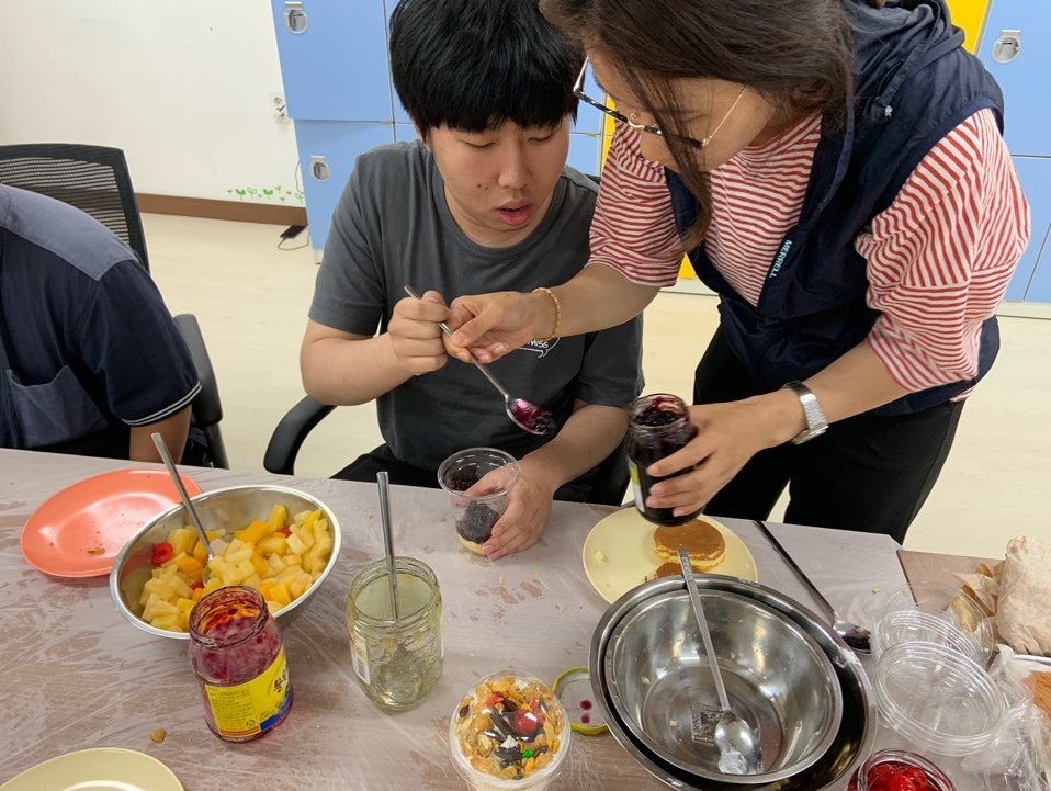 주간보호센터 이용자가 파르페를 만들기 위해 잼을 뜨고 있는 사진