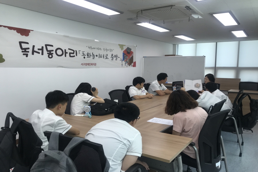 독서동아리에 참여한 학생들이 강사가 읽어주는 책을 바라보고 있는 모습