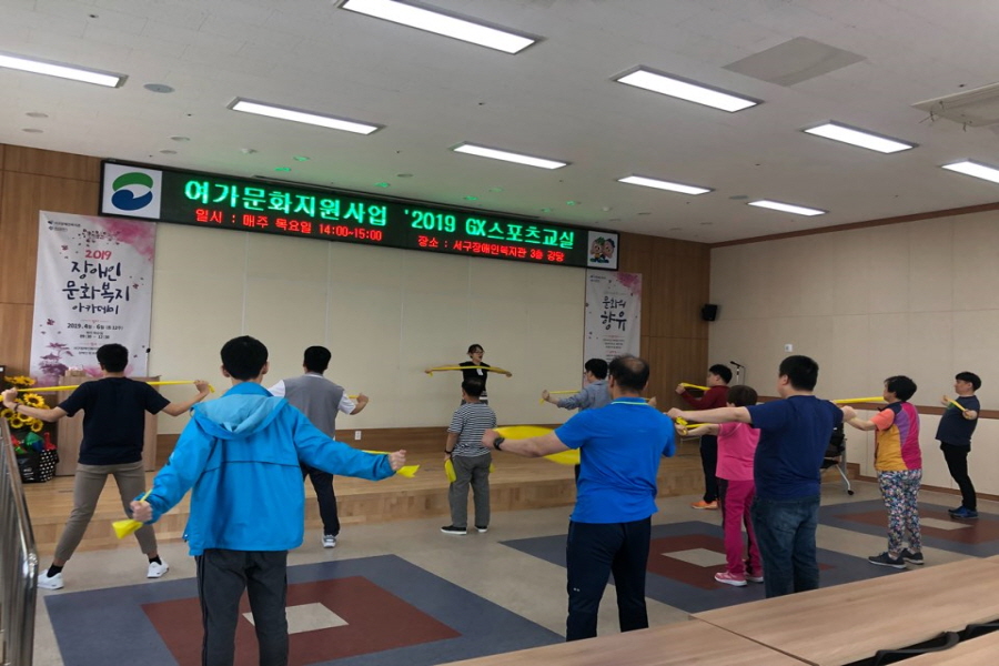 이용자들이 줄을 맞춰 서서 테라밴드를 활용하여 체조를 하는 모습