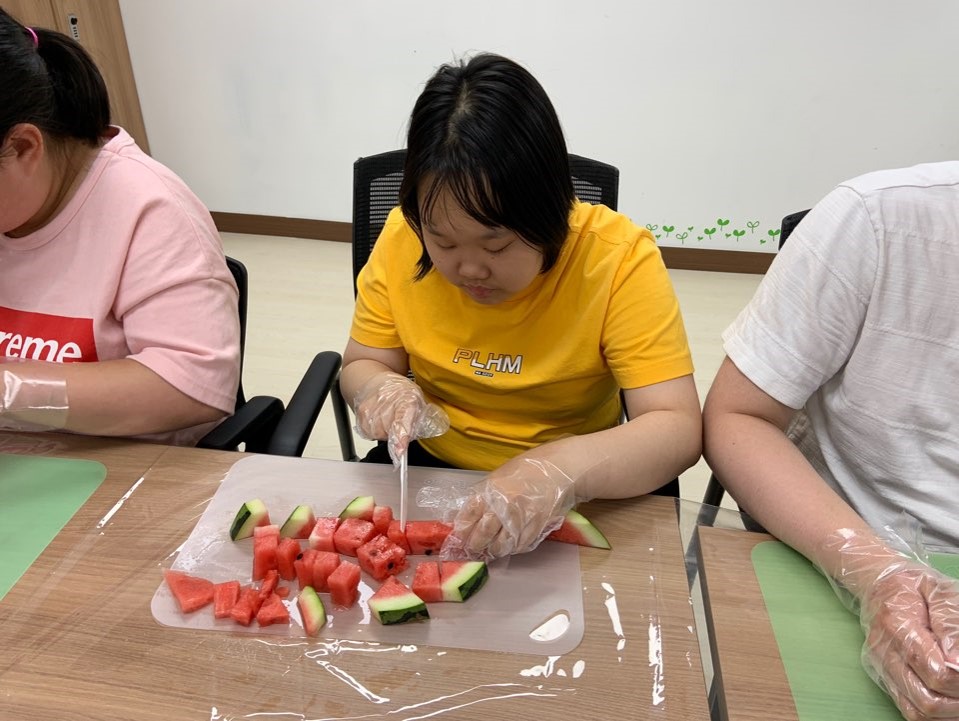 주간보호센터 이용자가 수박을 자르기 위해 사뭇진지한 표정으로 임하고 있는 모습