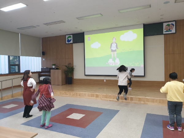 무용교실 참여아동들이 스크린에 나오고 있는 영상을 보고 이리저리 뛰어다니는 모습