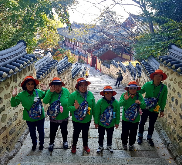 범어사로 가는 계단에서 찍은 기념사진 뒤로는 한옥들과 담벼락이 보인다.