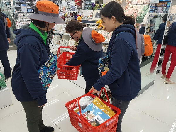 주간활동이용자들이 지역사회의 상점에 들러 물품구입체험을 진행하고 있는 모습 한 이용자가 바구니를 이리저리 만져보고 있다
