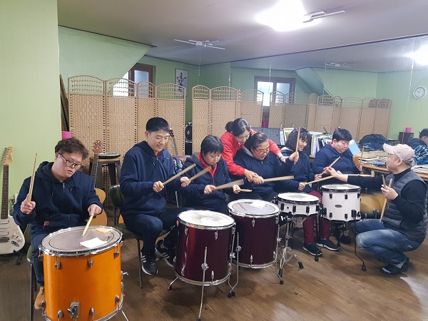 드럼교실에 참여하여 강사의 설명에 맞춰 드럼을 배우고 있는 모습
