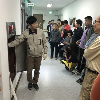 교육 참여자들이 옥내 소화전의 사용법에 대해 설명을 듣는 모습