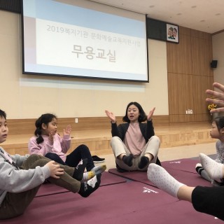 무용교실 강사가 참여아동들과 함께 다리를 들어올리며 활동을 진행하는 모습